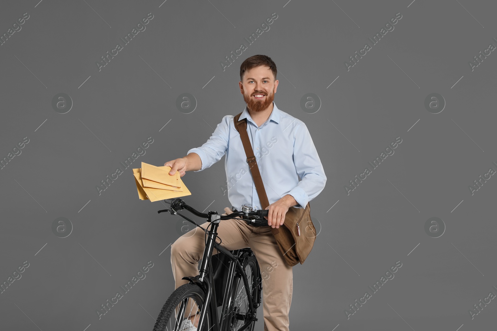 Photo of Postman on bicycle delivering letters against grey background