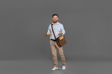 Postman with brown bag delivering letters on grey background