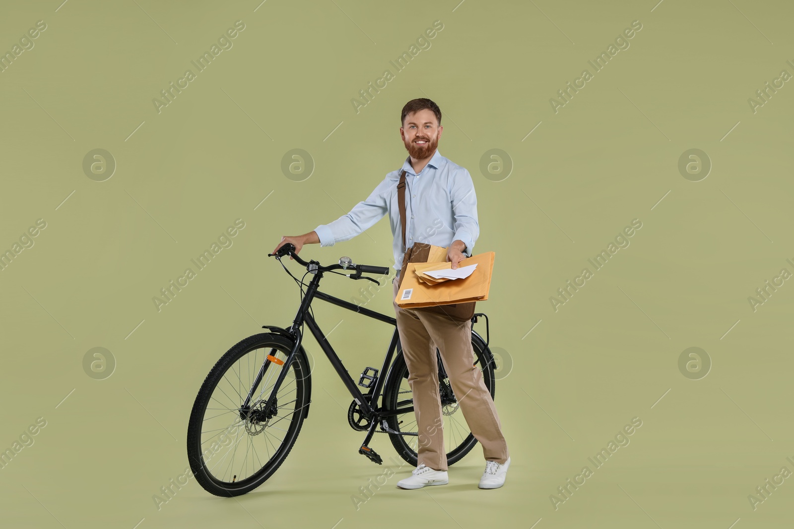 Photo of Postman with bicycle delivering letters on light green background