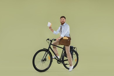 Postman on bicycle delivering letters against light green background