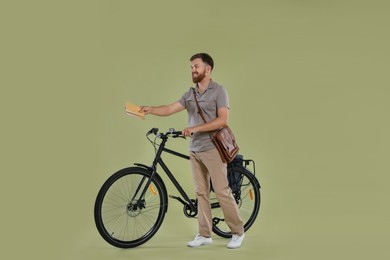 Photo of Postman with bicycle delivering letters on light green background