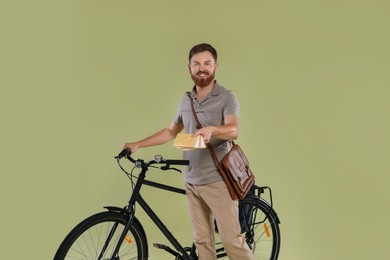 Photo of Postman with bicycle delivering letters on light green background