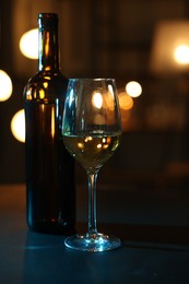 Photo of Tasty wine in glass and bottle on table against blurred lights