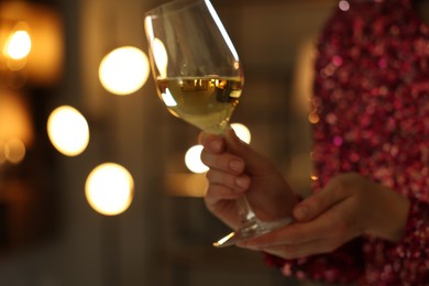 Photo of Woman with glass of wine against blurred lights, closeup