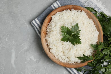 Tasty cooked rice in bowl with parsley on grey marble table, flat lay. Space for text