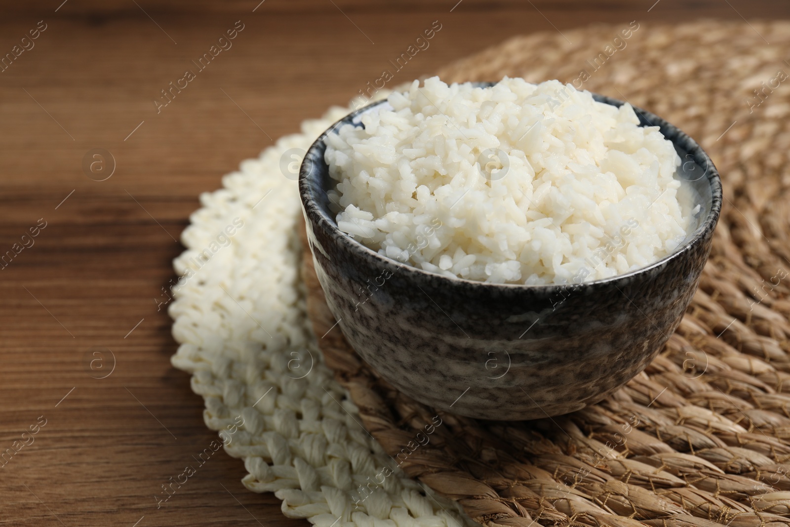 Photo of Tasty cooked rice in bowl on wooden table, closeup