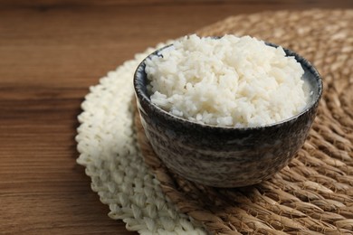 Tasty cooked rice in bowl on wooden table, closeup