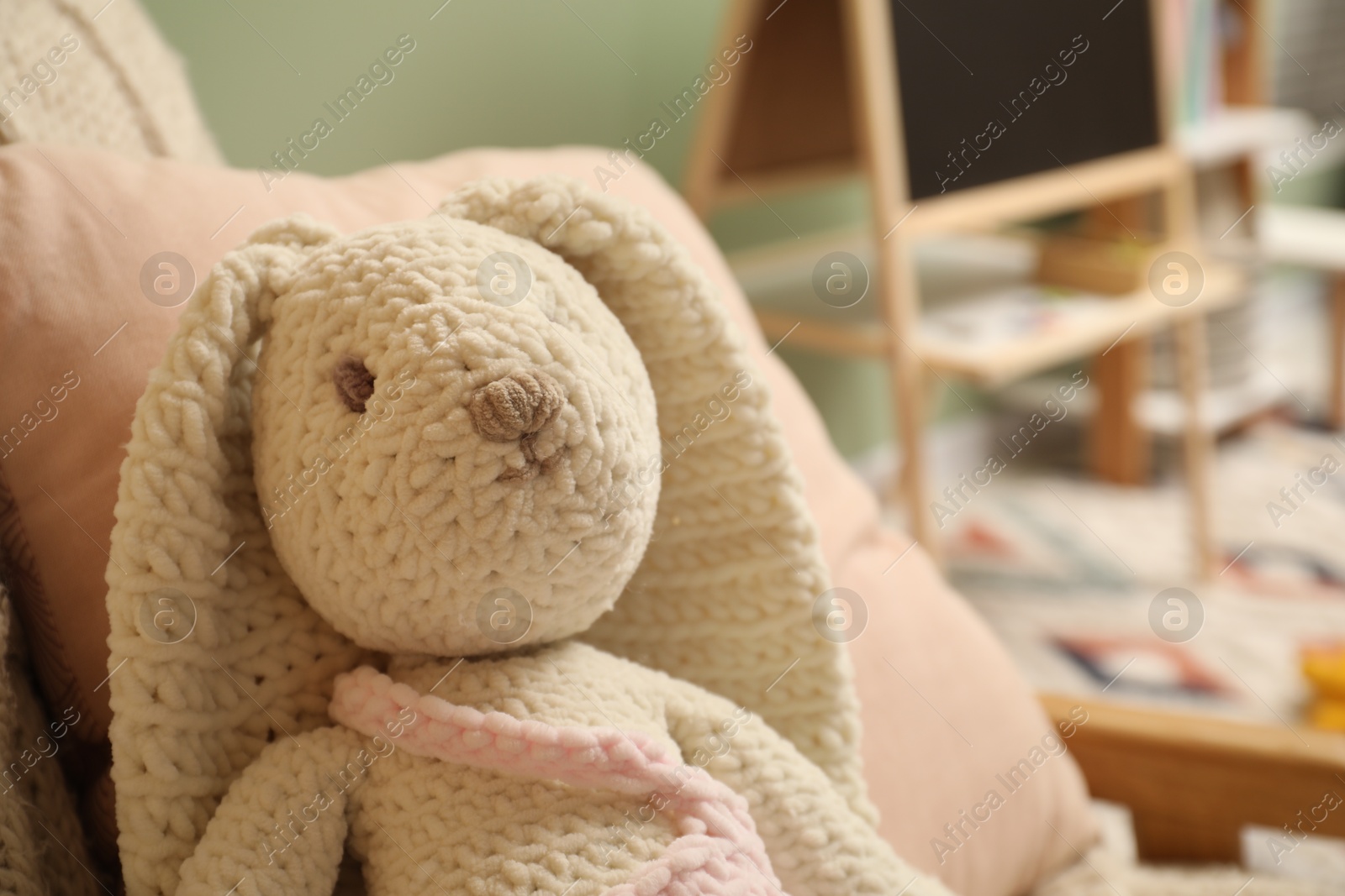 Photo of Cute bunny toy on armchair in child room