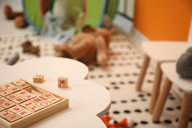 Photo of Wooden cubes on white table in child room, space for text