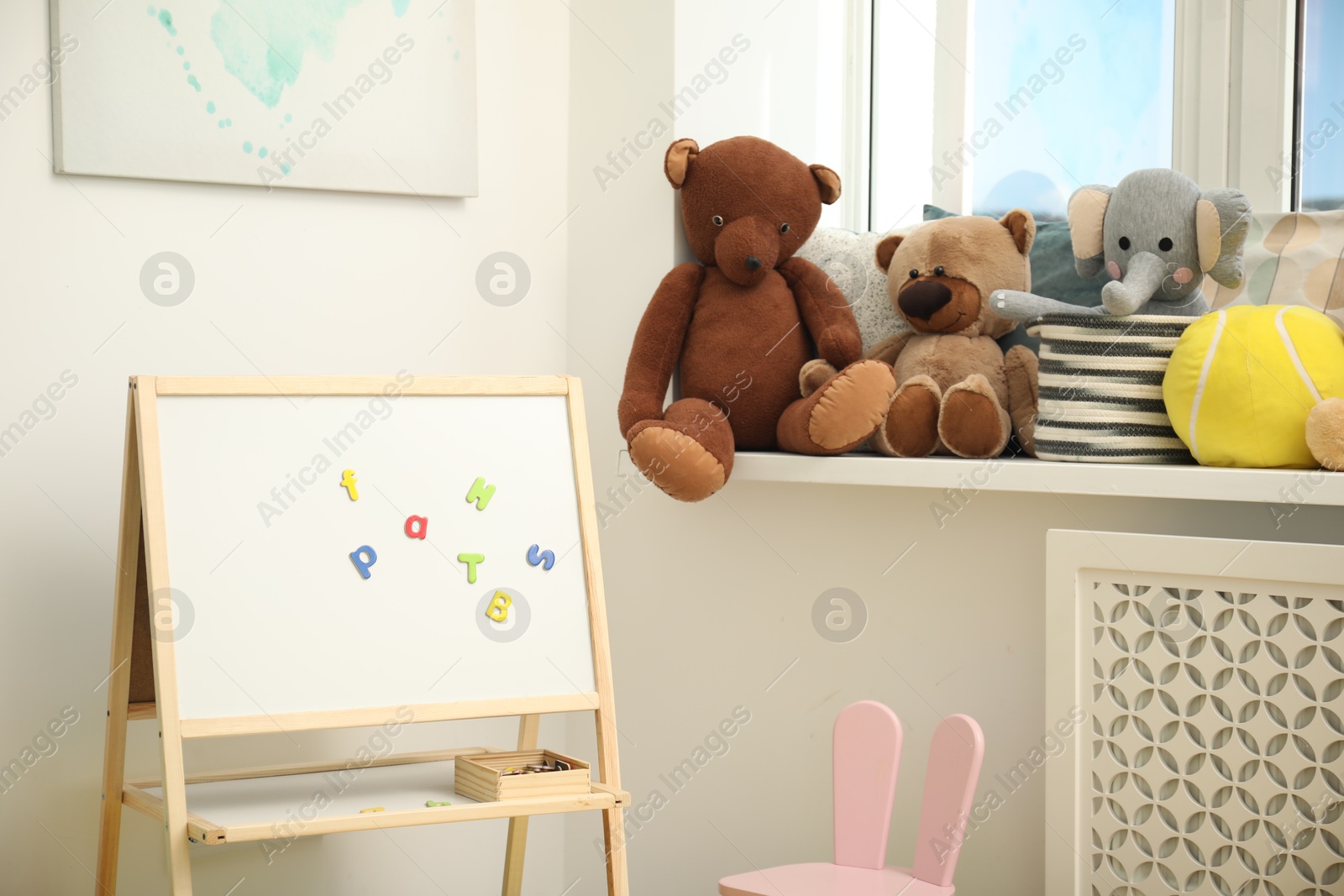 Photo of Different toys and board with magnetic letters in child room