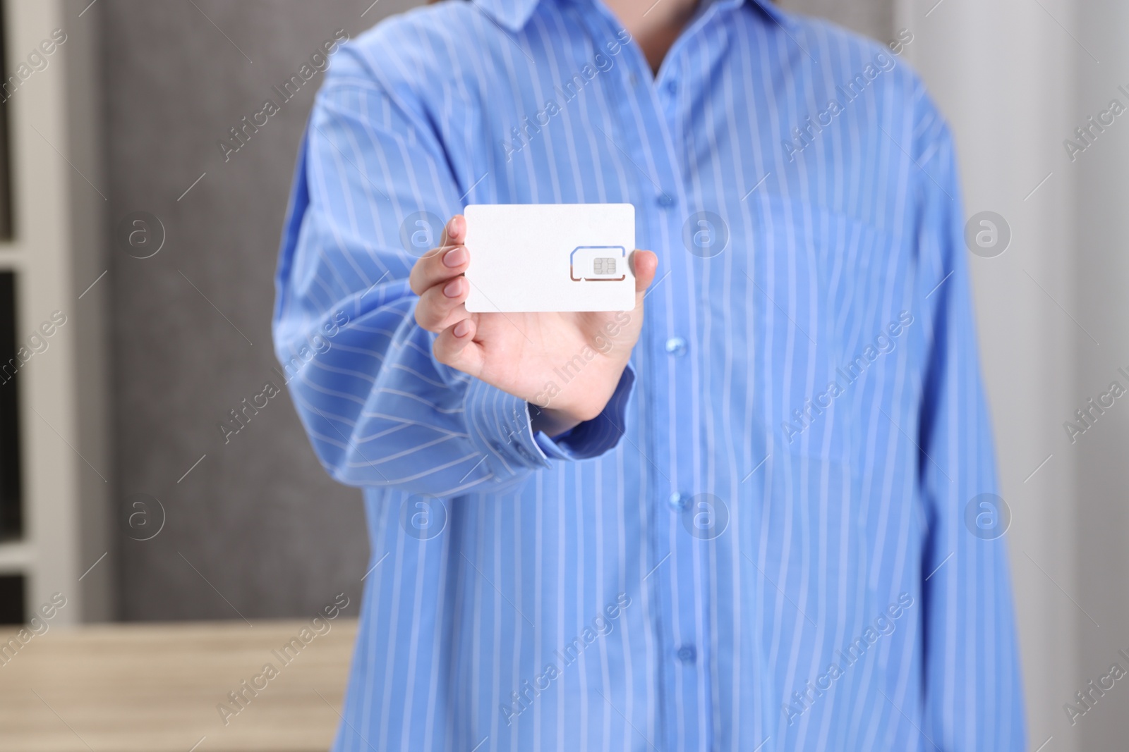 Photo of Woman holding SIM card indoors, closeup view