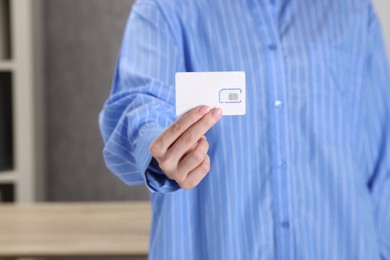 Photo of Woman holding SIM card indoors, closeup view