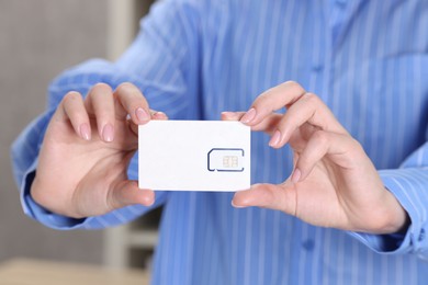 Photo of Woman holding SIM card indoors, closeup view