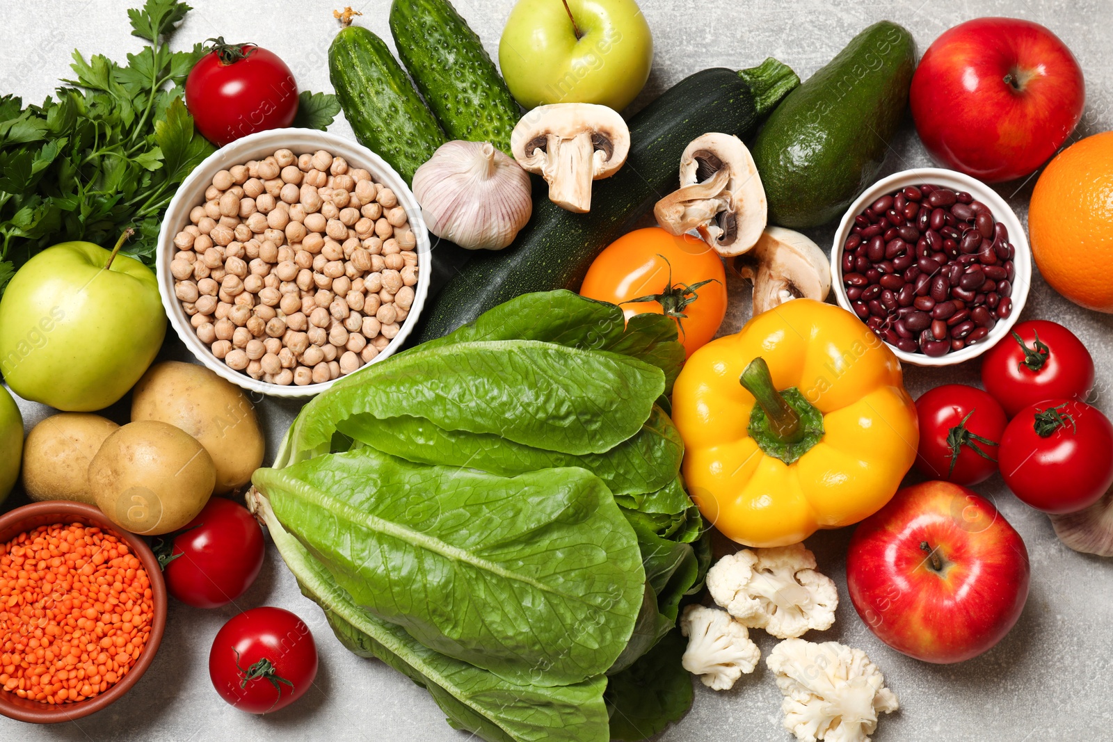 Photo of Healthy vegetarian food. Different vegetables, lentils and apples on grey textured table, flat lay