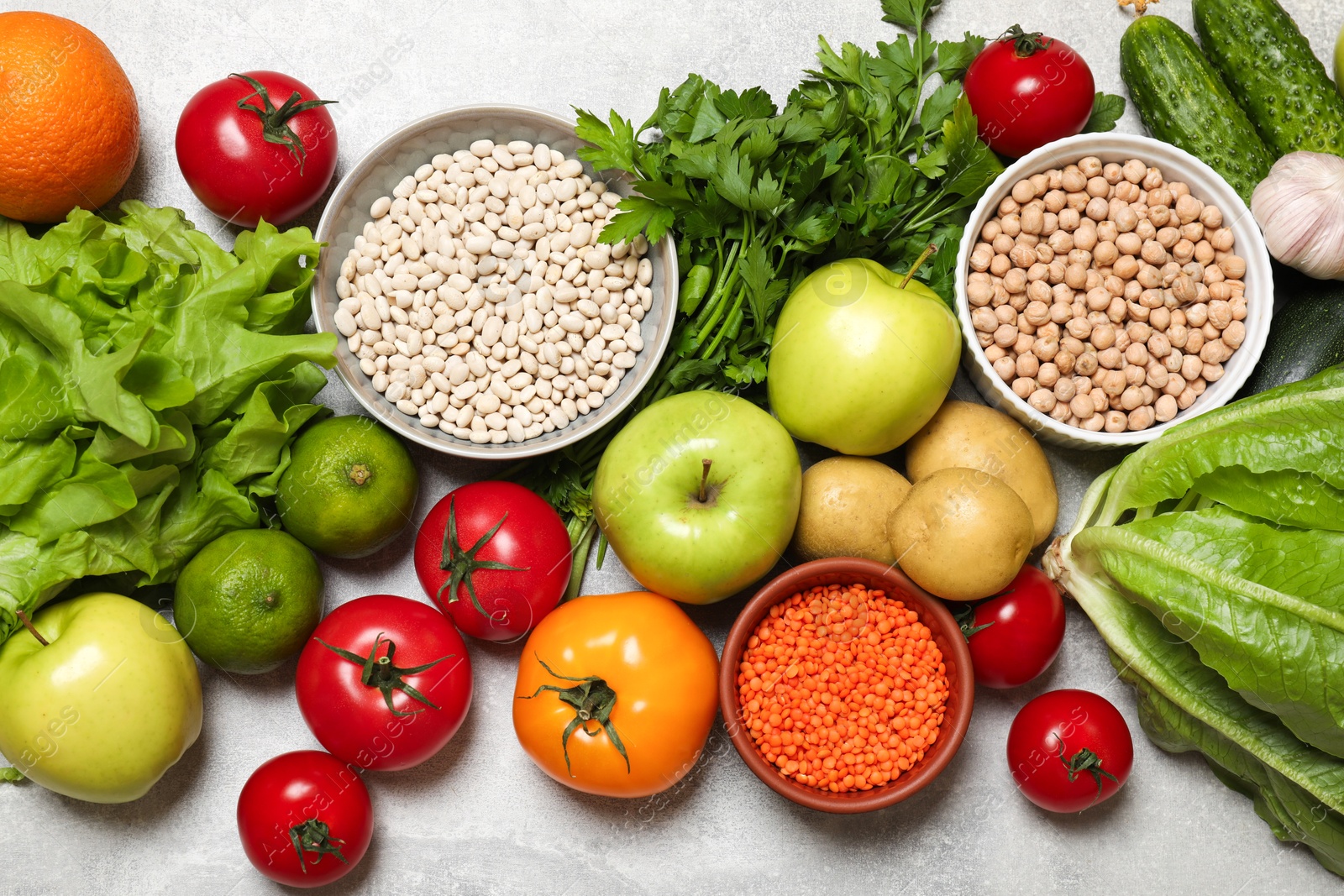 Photo of Healthy vegetarian food. Different vegetables, lentils and apples on grey textured table, flat lay