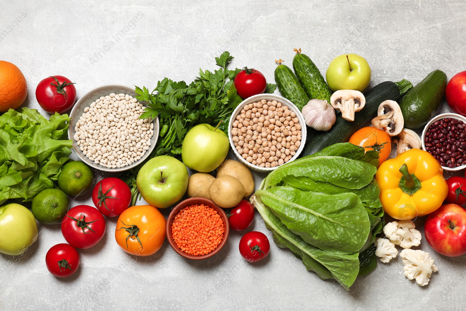 Photo of Healthy vegetarian food. Different vegetables, lentils and apples on grey textured table, flat lay