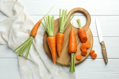 Fresh carrots and knife on white wooden table, flat lay