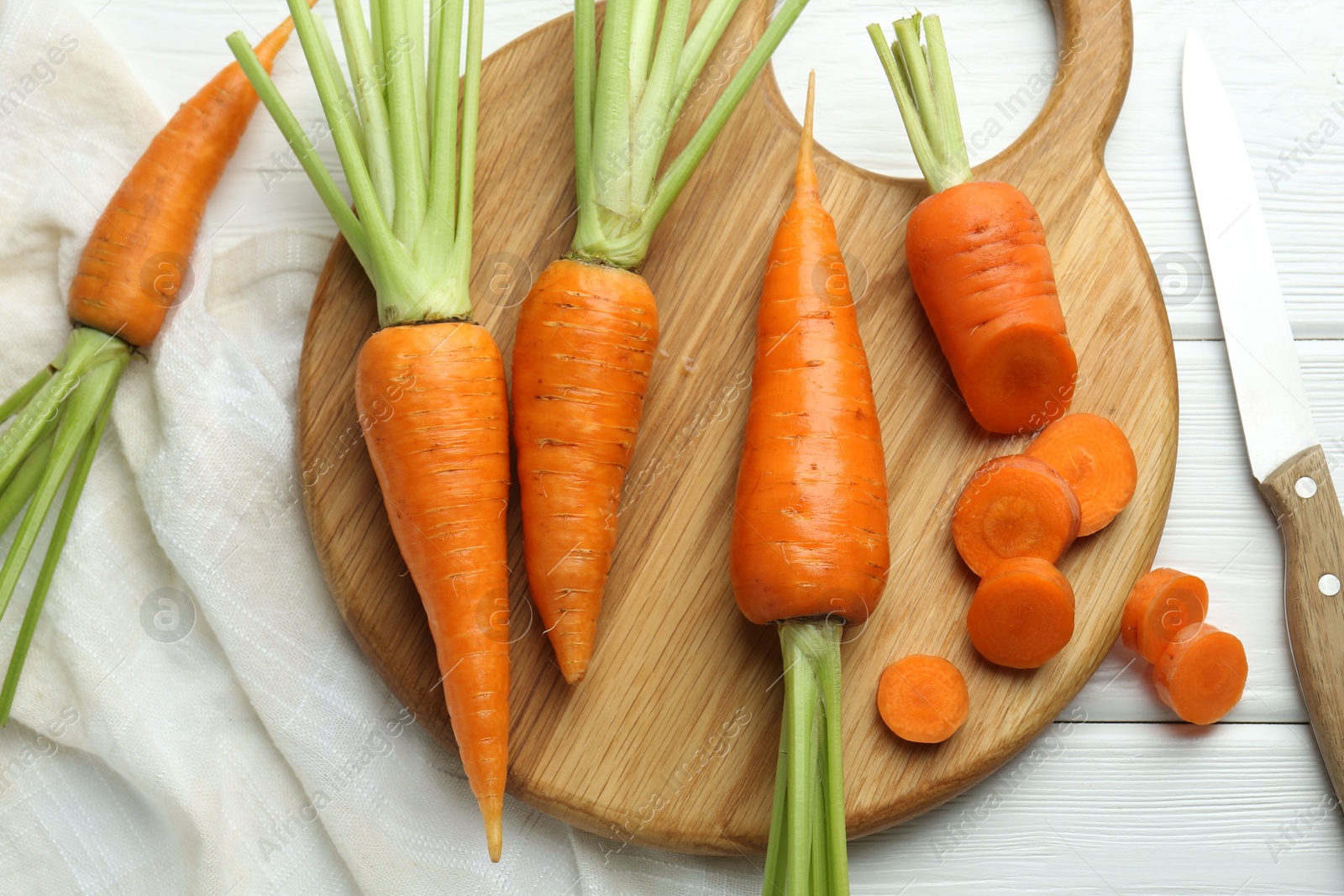 Photo of Fresh carrots and knife on white wooden table, flat lay