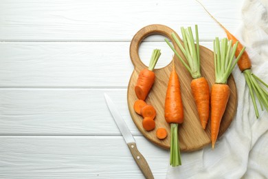 Fresh carrots and knife on white wooden table, flat lay. Space for text