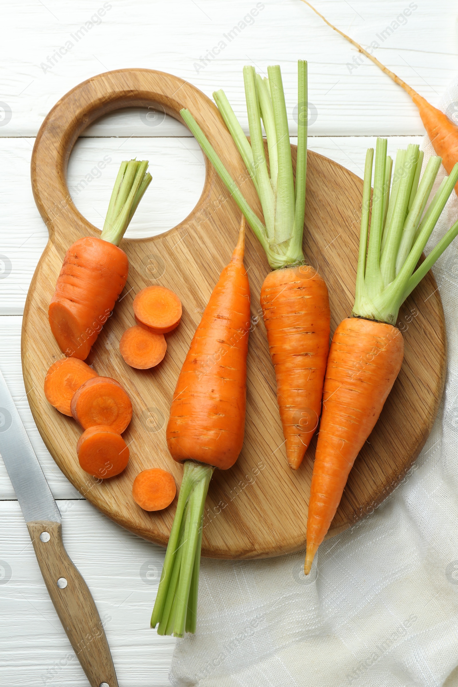 Photo of Fresh carrots and knife on white wooden table, flat lay