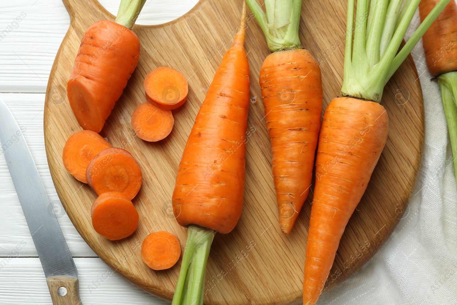 Photo of Fresh carrots and knife on white wooden table, flat lay