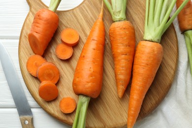 Fresh carrots and knife on white wooden table, flat lay