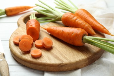 Photo of Whole and cut fresh carrots on white wooden table, closeup