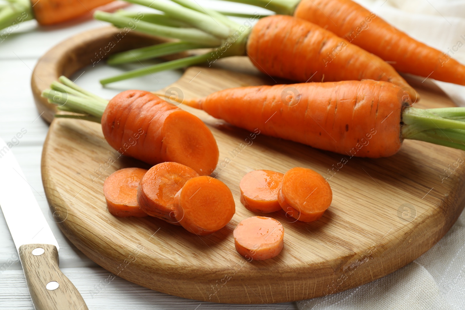 Photo of Fresh carrots and knife on white wooden table, closeup