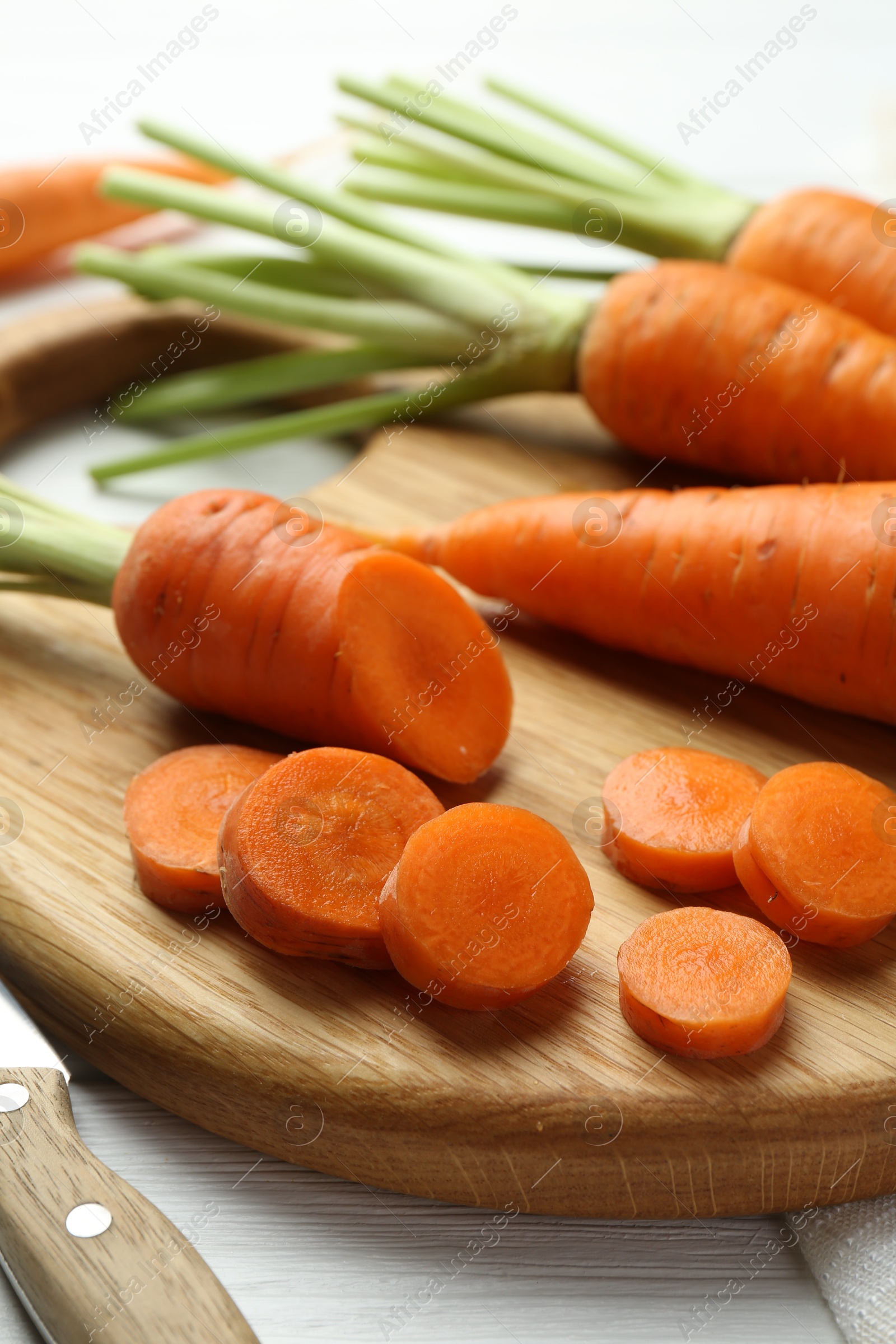 Photo of Whole and cut fresh carrots on white wooden table, closeup