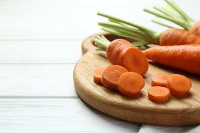 Photo of Whole and cut fresh carrots on white wooden table, closeup. Space for text