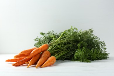 Tasty ripe juicy carrots on white wooden table