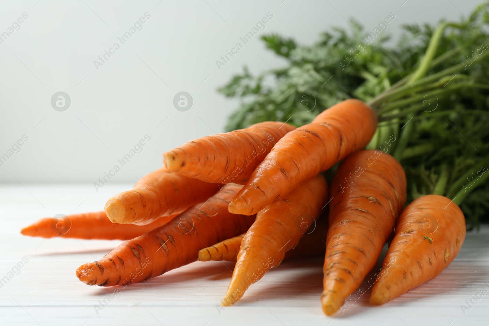 Photo of Tasty ripe juicy carrots on white wooden table, closeup