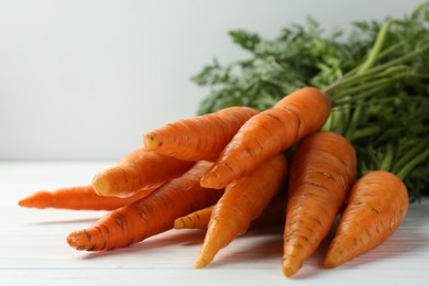 Tasty ripe juicy carrots on white wooden table, closeup