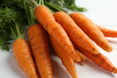 Photo of Tasty ripe juicy carrots on white wooden table, closeup