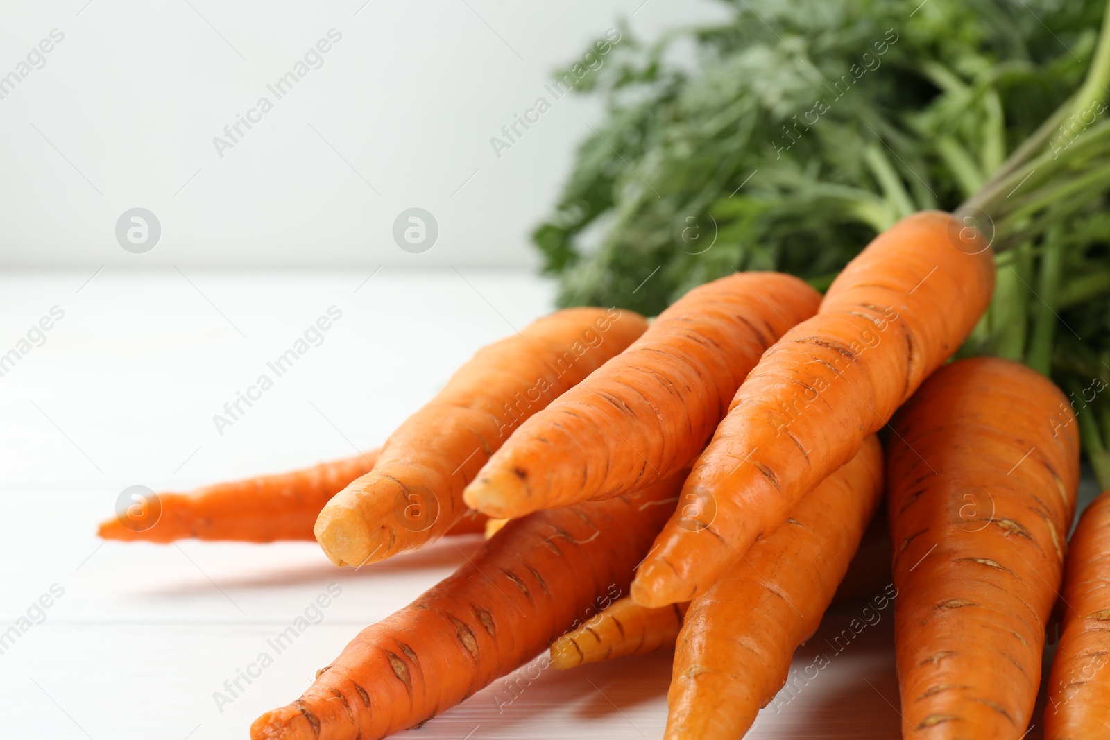 Photo of Tasty ripe juicy carrots on white wooden table, closeup