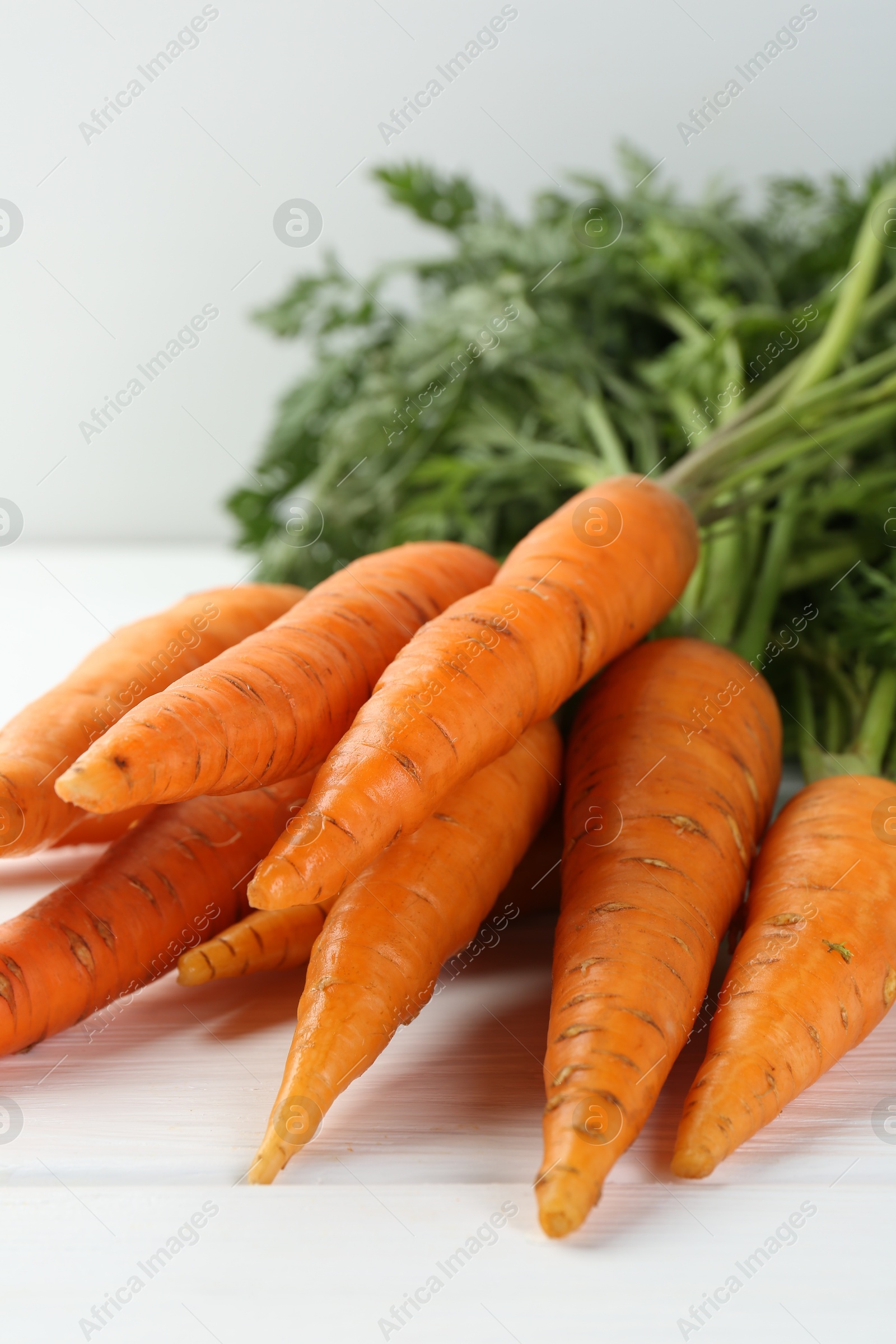 Photo of Tasty ripe juicy carrots on white wooden table, closeup