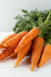 Tasty ripe juicy carrots on white wooden table, closeup