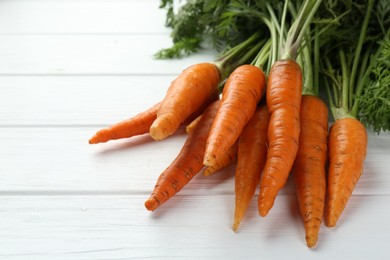 Photo of Tasty ripe juicy carrots on white wooden table, closeup. Space for text