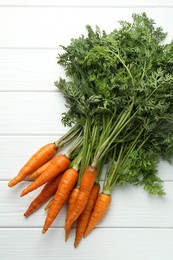 Photo of Tasty ripe juicy carrots on white wooden table, top view