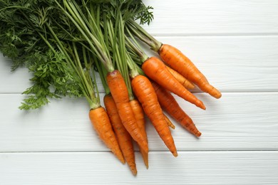 Tasty ripe juicy carrots on white wooden table, top view