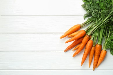 Photo of Tasty ripe juicy carrots on white wooden table, top view. Space for text