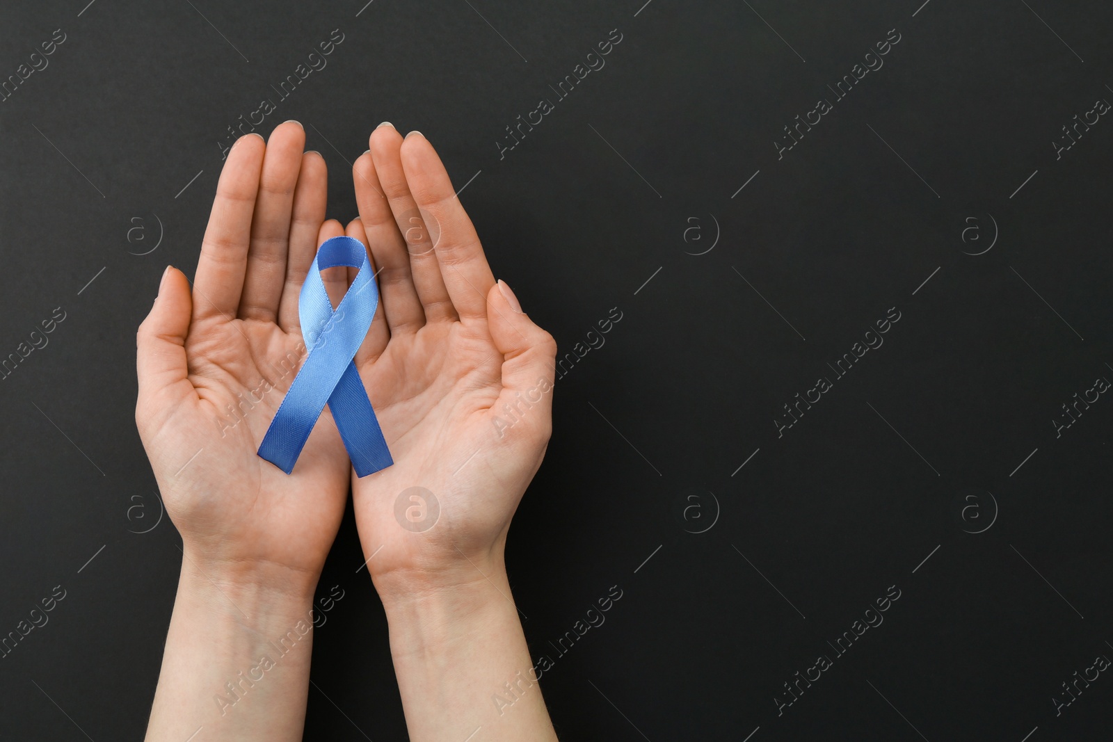 Photo of Woman with blue awareness ribbon on black background, top view. Space for text