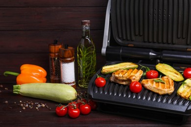 Photo of Electric grill with different products on wooden table