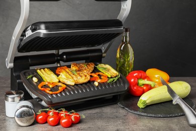 Electric grill with different products and knife on grey textured table