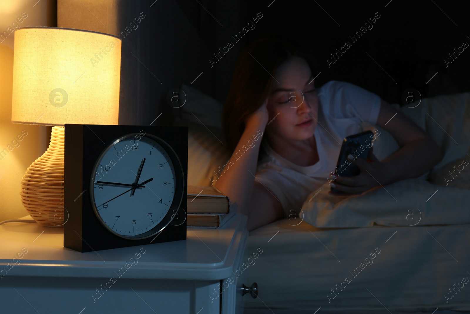 Photo of Woman using smartphone on bed at night, selective focus. Internet addiction