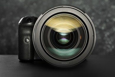 Modern photo camera on black table, closeup. Photographer's equipment