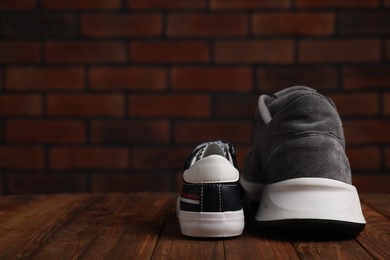 Photo of Big and small sneakers on wooden surface, space for text