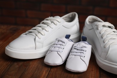 Photo of Big and small sneakers on wooden surface