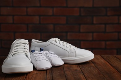 Big and small sneakers on wooden surface