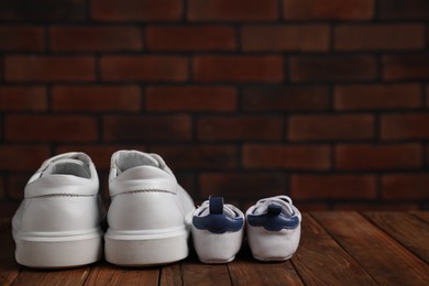 Photo of Big and small sneakers on wooden surface